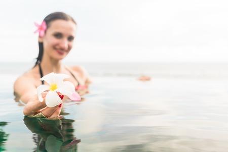 Woman in summer vacation relaxing swimming in pool with the ocean in the backgroundの写真素材