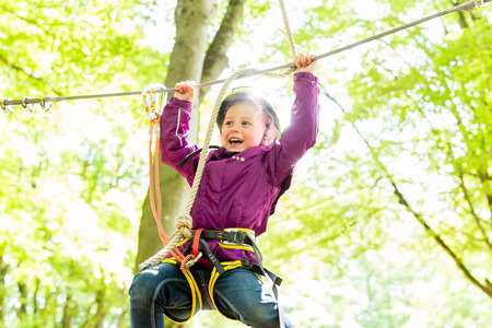 Girl climbing in high rope course enjoying the adventure