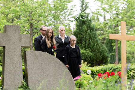 Family mourning at grave on graveyard or cemeteryの写真素材