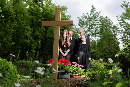 Family mourning at grave on graveyard or cemeteryの写真素材
