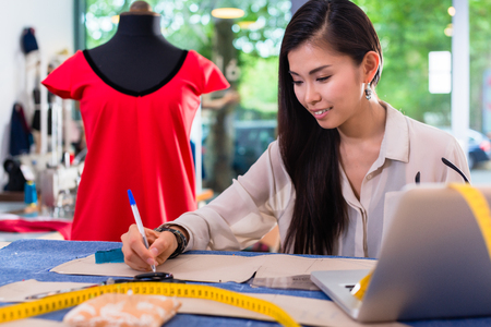 Asian fashion designer preparing drafts for cut-outsor her new collectionの写真素材