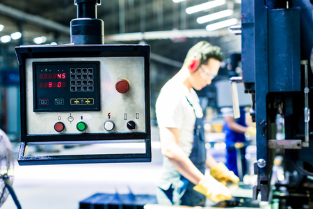 Asian machine operator in production plant checking data