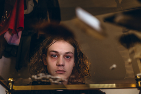 Low-angle view portrait of an addicted teenage boy staring while experiencing psychotropic effects caused by snorting cocaineの写真素材