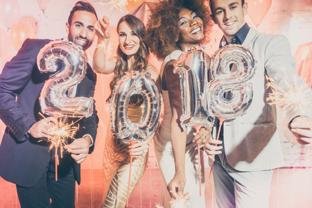 Party people women and men celebrating new years eve 2018 with sparklers and Champagne