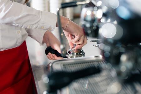 Close-up of the hands of a waiter preparing espresso at an automatic coffee machineの写真素材
