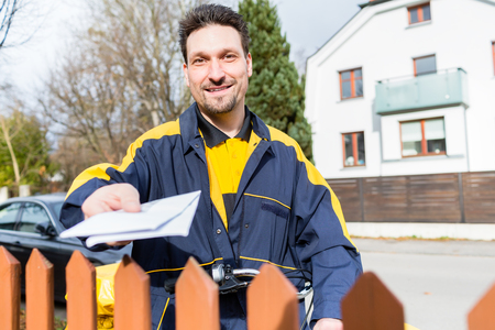 Mailman passing letters to addressee over fenceの写真素材