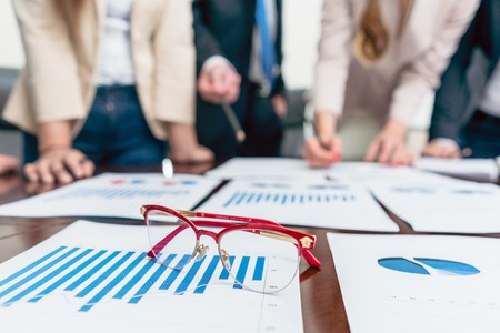 Close-up of eyeglasses with red frames on a printed bar chart showing progress during a meeting of business analysts, in the office of a successful companyの写真素材