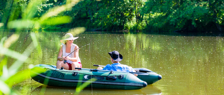 Couple in boat on pond or lake fishing, woman with angle and man is steeringの写真素材