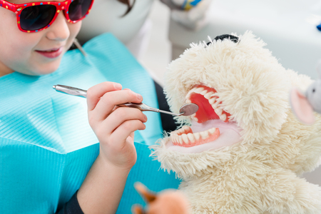 Child at dentist office looking after teeth of pet toyの写真素材