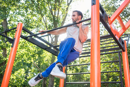 Low-angle view of a strong and determined young man doing amazing pull-up variation during extreme...