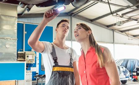 Low-angle view of an experienced auto mechanic checking the disk brake rotors of the car of a female customerの写真素材