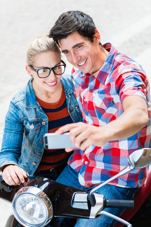 Young Couple, woman and man, on city trip in Berlin planning their Vespa tour using tablet PCの写真素材