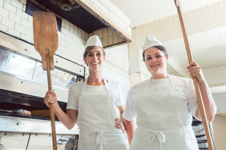 Team of baker women standing proudly in bakery giving thumbs upの写真素材