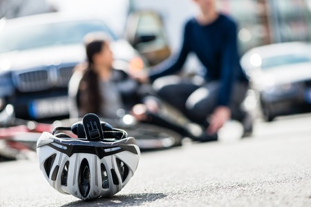 Close-up of a bicycling helmet fallen down on the ground after accidental collision between bicycle and a 4x4 carの写真素材