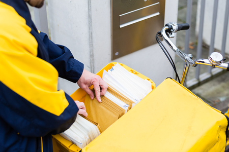 Postman delivering letters to recipient mailboxの写真素材