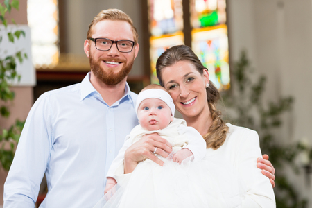 Young parents at the church with their baby wearing a christening gownの写真素材