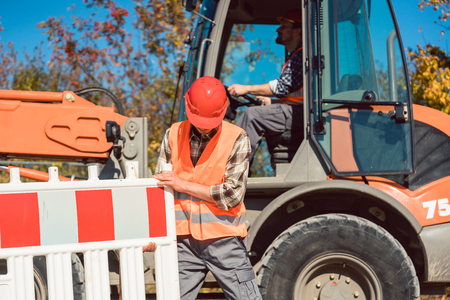 Worker setting up earthworks construction site erecting fence