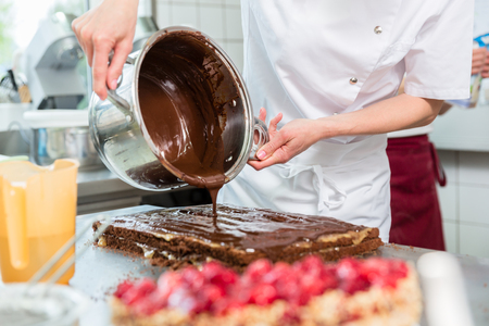 Confectioner or Patissier putting chocolate as frosting on cakeの写真素材
