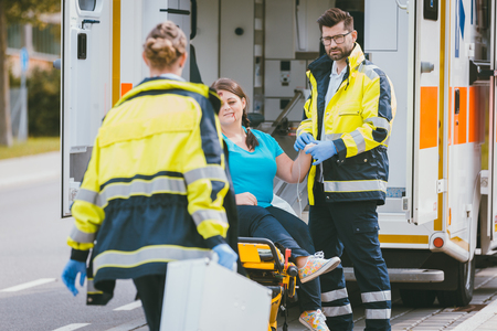 Medic and emergency doctor approaching site of accident with injured woman waitingの写真素材