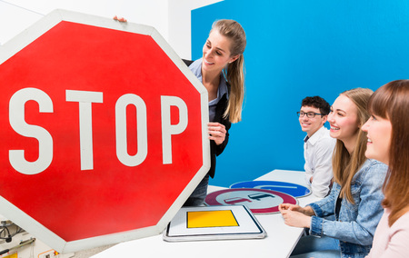 Driving teacher explaining meaning of street signs to class of students