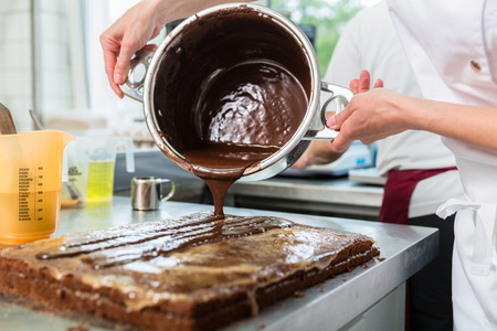 Confectioner or Patissier putting chocolate as frosting on cakeの写真素材