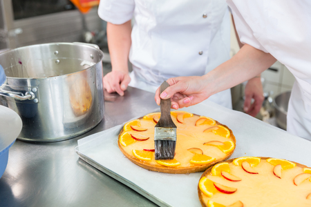 Fruit cakes being made by two pastry bakers or Patissiersの写真素材