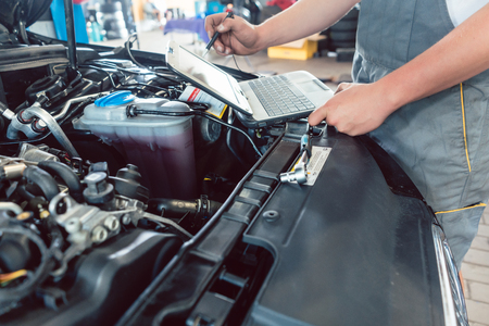 Close-up of a screwdriver held by a skilled mechanic, before repairing the engine after scanning the errors with a diagnostic software in a modern automobile repair shopの写真素材