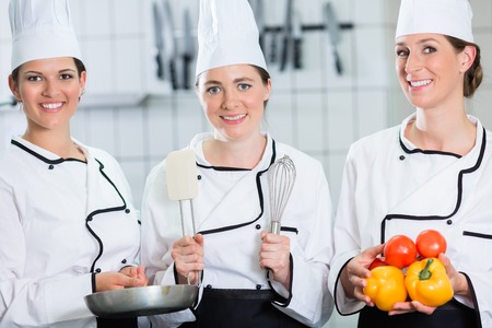 Chefs in commercial kitchen posing with food and crockeryの写真素材