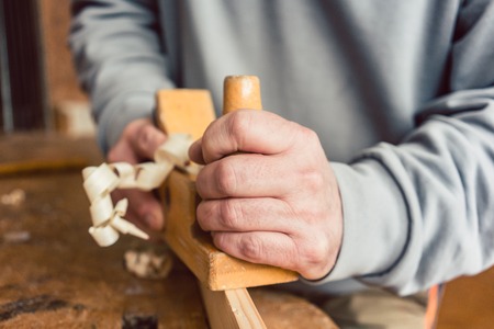Hand of a senior carpenter with wood planer, closeupの写真素材