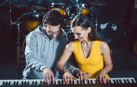 Piano teacher giving lessons to his student in music schoolの写真素材