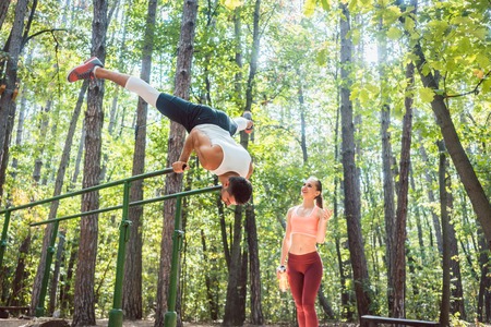 Sportive couple, woman and man, doing workout in outdoor gym