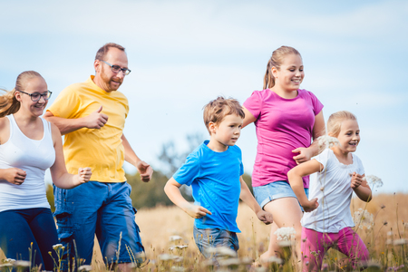 Family running for better fitness in summer jogging over a fieldの写真素材