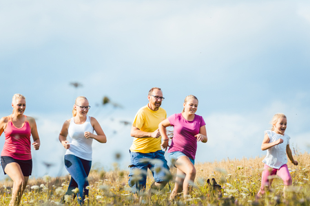Family running for better fitness in summer jogging over a fieldの写真素材