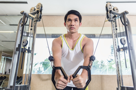 Low-angle view portrait of an Asian handsome man looking down with concentration while exercising...