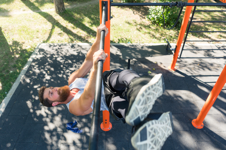 High-angle view of a strong and determined young man doing hanging oblique leg raises for abdominal...