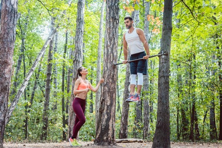 Strong man and athletic woman doing fitness and sport exercise in outdoor gym