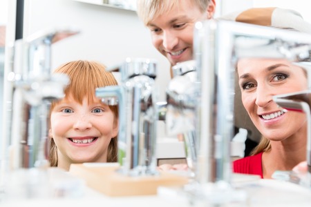 Low-angle portrait of a happy family, looking for a new bathroom sink faucet in a modern sanitary ware shop with high-quality fixtures and appliancesの写真素材