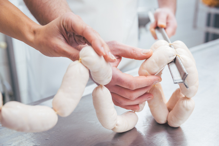 Butcher in butchery filling sausages on a chainの写真素材