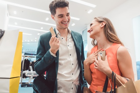 Happy Man having to pay with credit card for fashion items his wife shoppedの写真素材