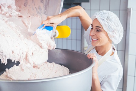 Woman working in butchery making minced meat checking quality
