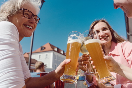 Three women drinking wheat beer on sunny day outdoorsの写真素材