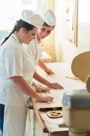 Baker women working in bakehouse of bakery looking into cameraの写真素材