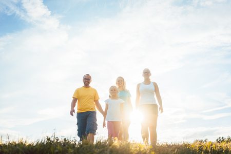 Family walking in sunset over a summer meadow, backlit sceneの写真素材