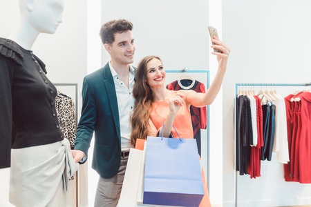 Couple doing selfie phone photo with their catch in fashion storeの写真素材