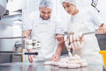 Team of butchers, woman and man, filling sausage in meat industryの写真素材