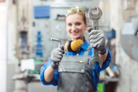Woman mechanic showing tools to the camera holding wrench in her handの写真素材