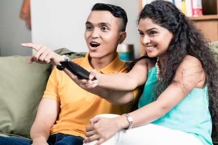 Couple watching television while woman using remote control