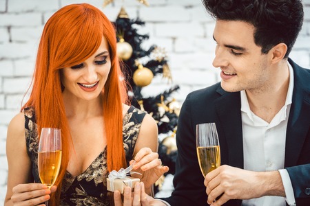 Man giving his wife present for Christmas, both drink sparkling wineの写真素材