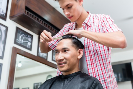 Close-up of barber combing the customers hair with combの写真素材