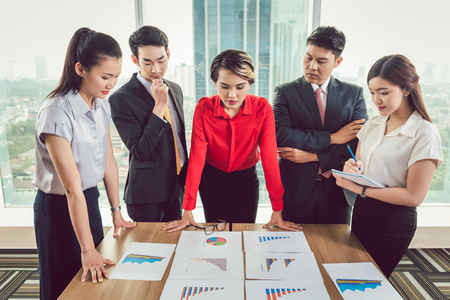 Group of businesspeople analyzing different business charts arranged on desk at workplaceの写真素材